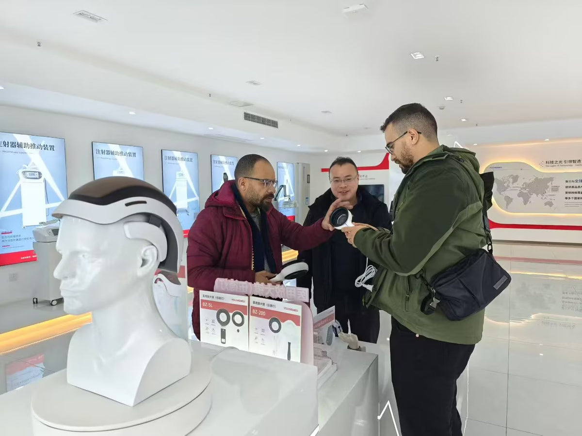Visitors discussing a YouWeMed light-care device during a customer visit
